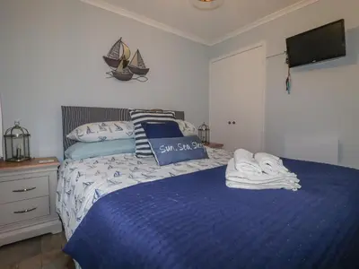 a bedroom with a bed with a blue comforter at Merryfield Lodge in Liskeard