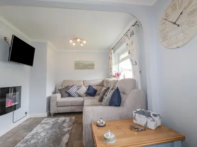 a living room with a couch and a clock on the wall at Merryfield Lodge in Liskeard