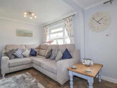 a living room with a couch and a clock on the wall at Merryfield Lodge in Liskeard