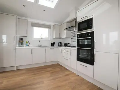 a white kitchen with white cabinets and a window at Acorn Lodge in Redruth