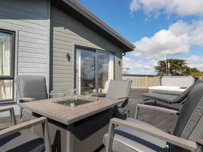 a patio with chairs and a table on a deck at Acorn Lodge in Redruth