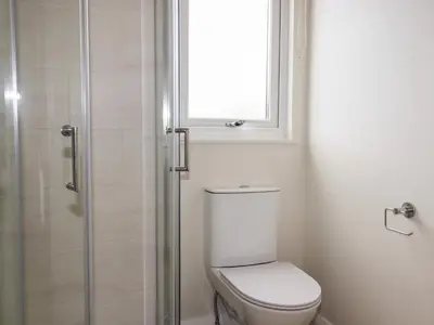 a bathroom with a toilet and a window and a shower at Acorn Lodge in Redruth