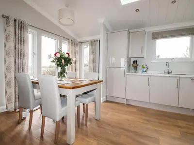 a kitchen with a table with chairs and a vase of flowers at Acorn Lodge in Redruth