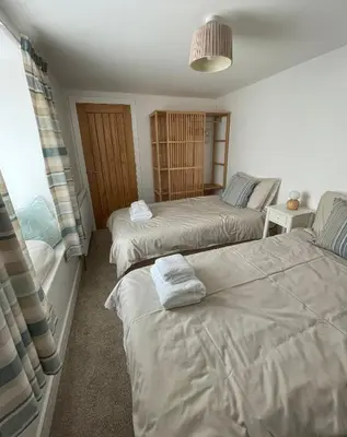 a bedroom with two beds and a window at Cliff House - a stunning sea view 2 bed apartment in Porthleven in Porthleven