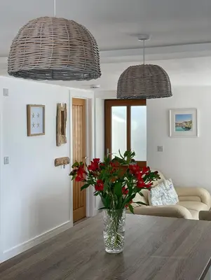 a vase of flowers on a table in a living room at Cliff House - a stunning sea view 2 bed apartment in Porthleven in Porthleven