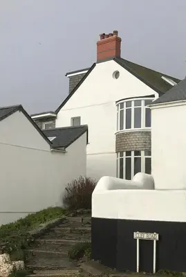 a white house with a sign in front of it at Cliff House - a stunning sea view 2 bed apartment in Porthleven in Porthleven