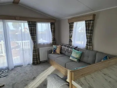 a living room with a couch and windows at Mawgan Pads Perranporth in Cubert