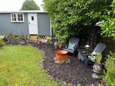 a garden with two chairs and a bird bath and a table at Miners Hut in St Austell