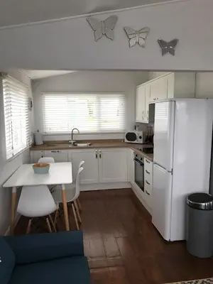 a kitchen with a white refrigerator and a table and chairs at Holiday Chalet at Gwithian Sands in Cornwall in Gwithian