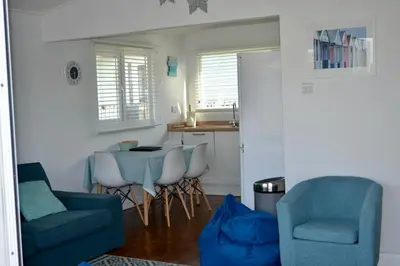 a living room with a table and chairs and a kitchen at Holiday Chalet at Gwithian Sands in Cornwall in Gwithian