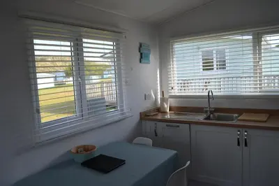 a kitchen with a table and a sink and two windows at Holiday Chalet at Gwithian Sands in Cornwall in Gwithian