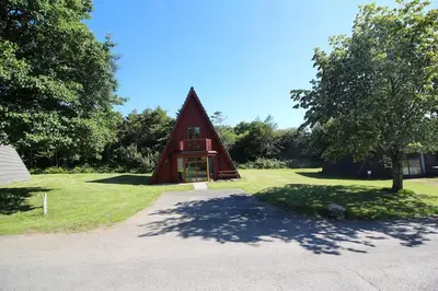 a small red house sitting on top of a lush green field at Lodges in Lanivet Cornwall with indoor pool in Bodmin