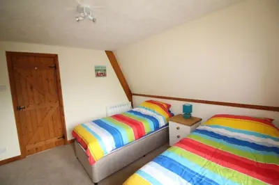a bedroom with two beds with colorful striped sheets at Lodges in Lanivet Cornwall with indoor pool in Bodmin