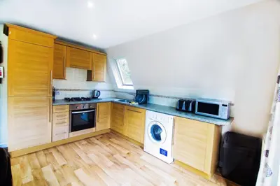 a kitchen with wooden cabinets and a washer and dryer at Lodges in Lanivet Cornwall with indoor pool in Bodmin