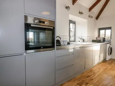 a kitchen with stainless steel appliances and wooden floors at Beacon Barn in St. Agnes