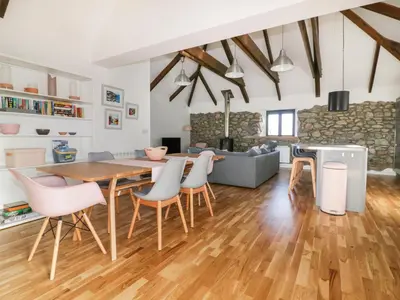 a kitchen and living room with a wooden table and chairs at Beacon Barn in St. Agnes