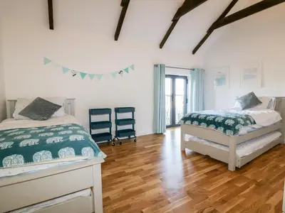 a bedroom with two beds and a wooden floor at Beacon Barn in St. Agnes