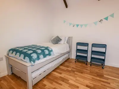 a bedroom with a bed and two blue chairs at Beacon Barn in St. Agnes