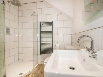 a white bathroom with a sink and a shower at Beacon Barn in St. Agnes