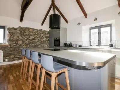 a kitchen with a large counter with chairs around it at Beacon Barn in St. Agnes