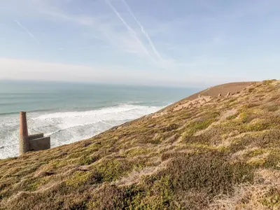 a grassy hill with the ocean in the background at Beacon Barn in St. Agnes