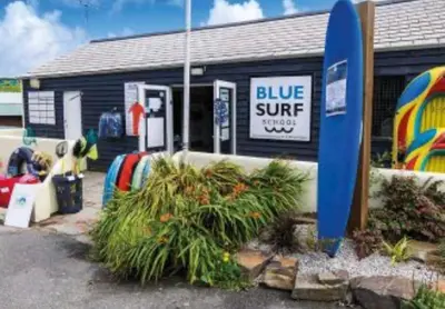 a blue surf shop with plants in front of it at Mollys Retreat pet friendly three bed caravan with small garden Newquay Bay Resort Quieter area of park in Newquay