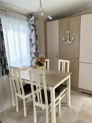 a kitchen with a wooden table and chairs and a window at Mollys Retreat pet friendly three bed caravan with small garden Newquay Bay Resort Quieter area of park in Newquay