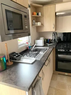 a kitchen with a stove and a microwave at Mollys Retreat pet friendly three bed caravan with small garden Newquay Bay Resort Quieter area of park in Newquay