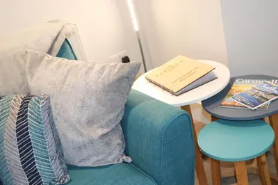 a side table with a blue couch and a table with a book at Townhouse, close to harbour with sea views in Padstow