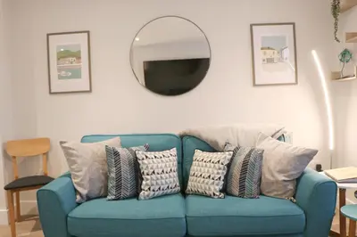 a blue couch with pillows in a living room with a mirror at Townhouse, close to harbour with sea views in Padstow