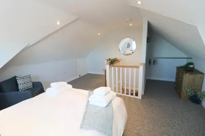 a bedroom with a white bed and a staircase at Townhouse, close to harbour with sea views in Padstow