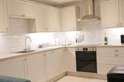 a white kitchen with white cabinets and a sink at Townhouse, close to harbour with sea views in Padstow