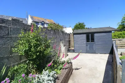 a garden with a retaining wall and a garage at Townhouse, close to harbour with sea views in Padstow