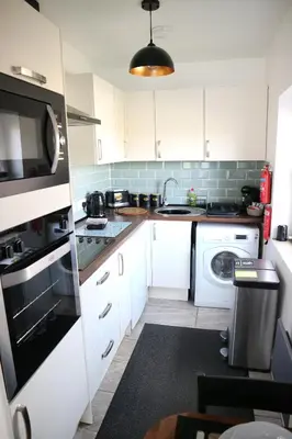 a kitchen with white cabinets and a washer and dryer at 12a Mault-Ley Studio in St Ives