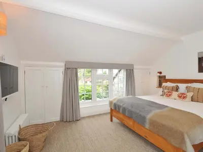 a white bedroom with a bed and a window at Island House in Fowey