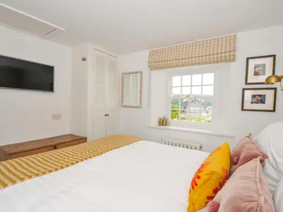 a white bedroom with a bed and a television at Island House in Fowey