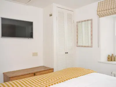 a bedroom with a bed and a tv on the wall at Island House in Fowey