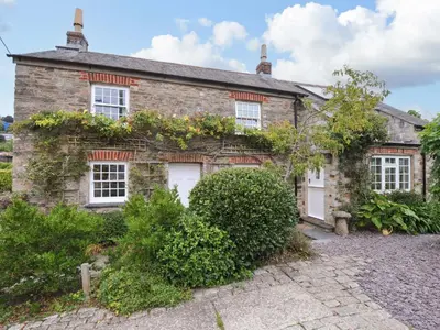 an old stone house with white doors and flowers at Island House in Fowey
