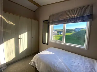 a bedroom with a bed and a large window at Daphne's Lodge in Mawgan Porth