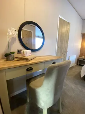 a mirror sitting on top of a desk with a chair at Daphne's Lodge in Mawgan Porth