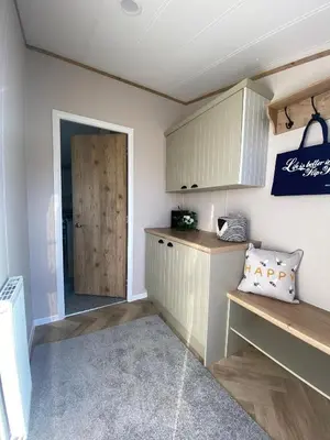 a kitchen with white cabinets and a wooden counter top at Daphne's Lodge in Mawgan Porth