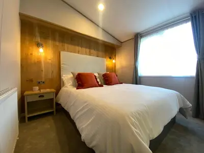 a bedroom with a large white bed and a window at Daphne's Lodge in Mawgan Porth