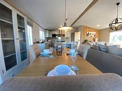 a dining room table with plates and glasses on it at Daphne's Lodge in Mawgan Porth