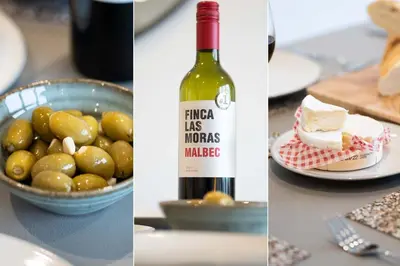 a bottle of wine and a bowl of olives and a plate of cheese at Del Mar in St Ives
