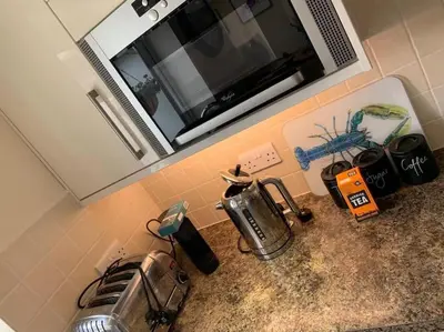 a kitchen counter with a microwave above a sink at 44 Raleigh Close@Padstow in Padstow