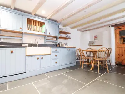 a kitchen with white cabinets and a table and chairs at Trelash Cottage in Launceston