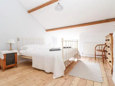 a white bedroom with a bed and a tv at Trelash Cottage in Launceston