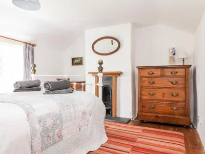 a bedroom with a bed and a dresser and a mirror at Trelash Cottage in Launceston