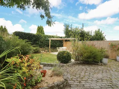 a garden with a wooden fence and a stone patio at Trelash Cottage in Launceston