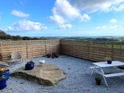 a patio with a table and a bench and a fence at The Neyth in Budock Water